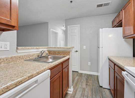 A kitchen with white appliances and brown cabinets.